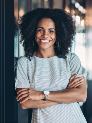 Jonge vrouw kijkt lachend in de camera met haar armen over elkaar