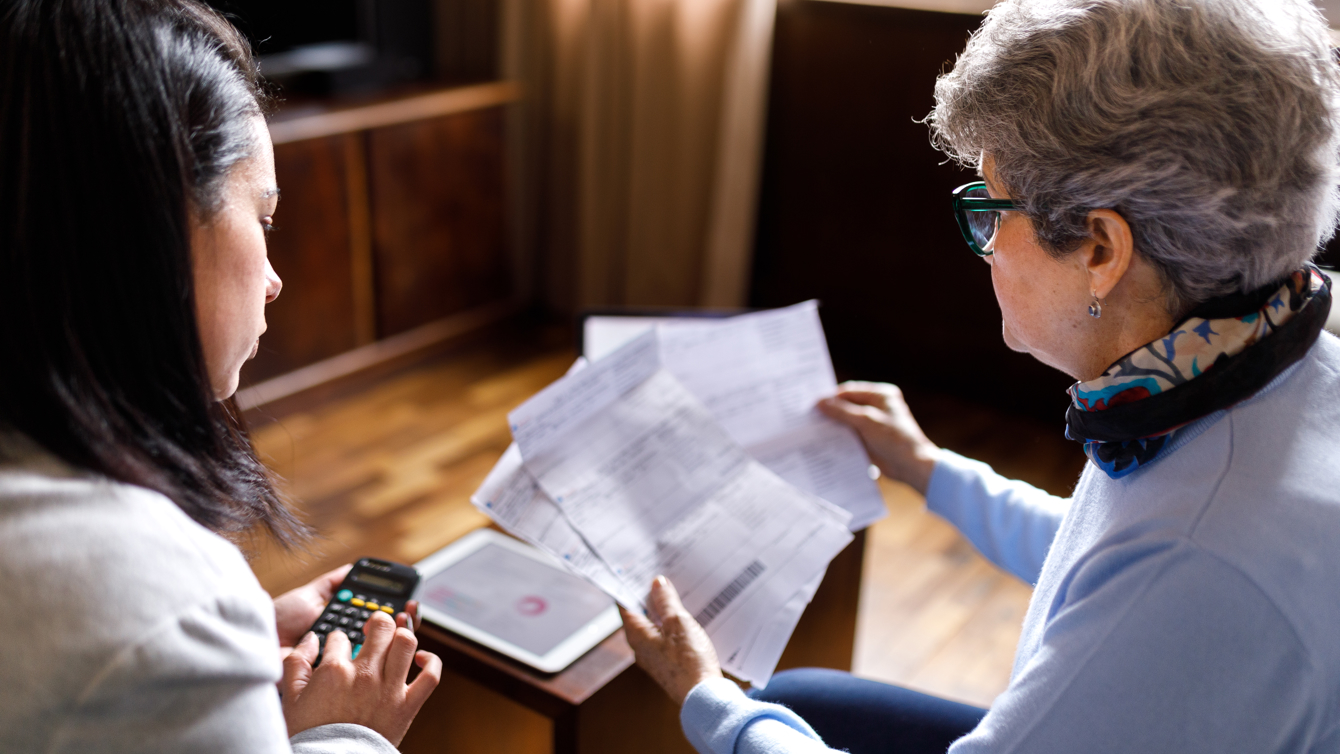 Oudere vrouw krijgt rekenhulp met papieren van een jonge vrouw