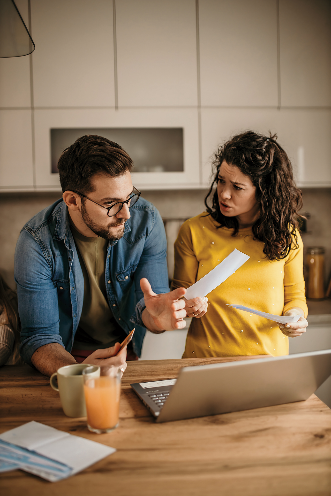Jong stel hangend aan een keukenblad met enveloppen in hun hand voor een laptop